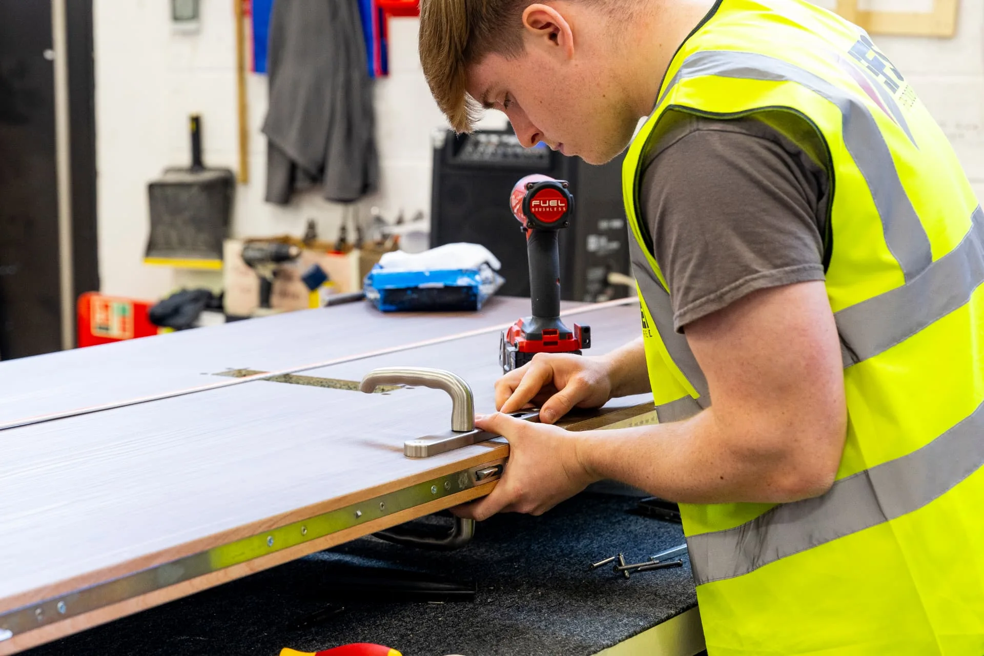 EFS technician fitting a handle to a timber fire door in the workshop